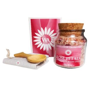 A jar of rose scented bath salts with a wooden scoop and muslin bag